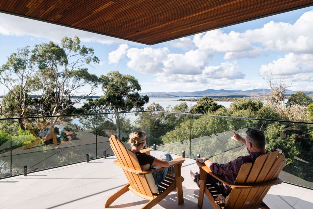 Steel sheet vs timber cladding -Glass-railed balcony with timber cladding, showcasing benefits for Australian weather